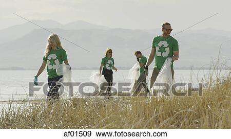Volunteers collecting recycling and trash garbage on remote grassy lake shore View Large Photo Image Stock Photo - Volunteers collecting recycling and trash garbage on remote grassy lake shore. Fotosearch