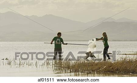 Volunteers working together and collecting recycling and trash garbage on remote grassy lake shore View Large Photo Image Stock Image - Volunteers working together and collecting recycling and trash garbage on remote grassy lake shore. Fotosearch