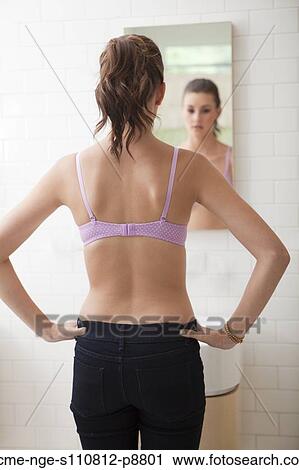 Stock Image - Young attractive woman looking into mirror. Fotosearch
