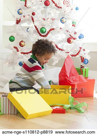 Young boy sitting under Christmas tree, opening Christmas presents View Large Photo Image Stock Photo - Young boy sitting under Christmas tree, opening Christmas presents. Fotosearch