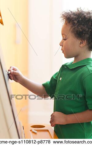 Young boy standing drawing on small blackboard with chalk View Large Photo Image Stock Photo - Young boy standing drawing on small blackboard with chalk. Fotosearch