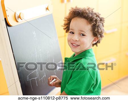 Young boy standing next to small blackboard, holding chalk View Large Photo Image Stock Photography - Young boy standing next to small blackboard, holding chalk. Fotosearch