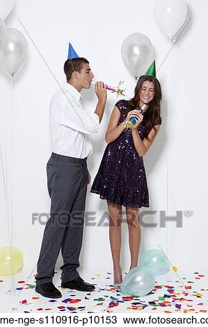 Young couple blowing horns at party View Large Photo Image Stock Image - Young couple blowing horns at party. Fotosearch