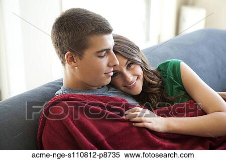 Stock Photography - Young couple sofa resting on sofa. Fotosearch