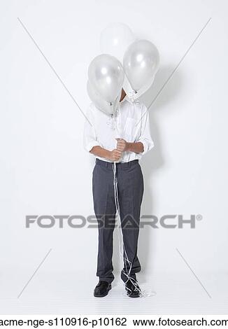 Young man hiding behind balloons at party View Large Photo Image Stock Image - Young man hiding behind balloons at party. Fotosearch