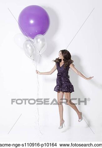 Young woman holding balloons, floating at party View Large Photo Image Picture - Young woman holding balloons, floating at party. Fotosearch