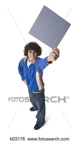 Stock Photograph - High angle view of a teenage boy holding a blank sign and smiling. Fotosearch