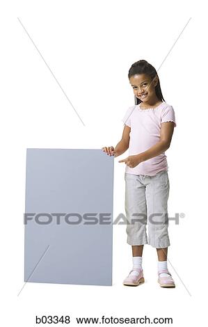 Stock Photo - Portrait of a young girl holding and pointing at a blank sign. Fotosearch