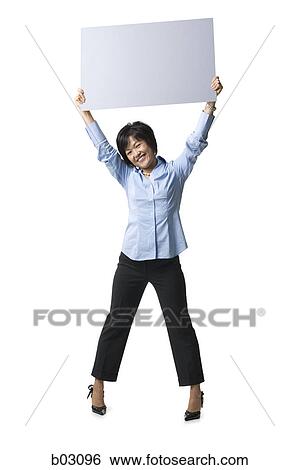 Stock Photograph - Portrait of a mid adult woman holding up a blank sign. Fotosearch