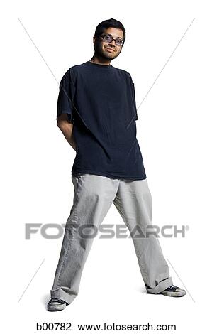 Stock Image - Portrait of a young man standing with his hands behind his back. Fotosearch