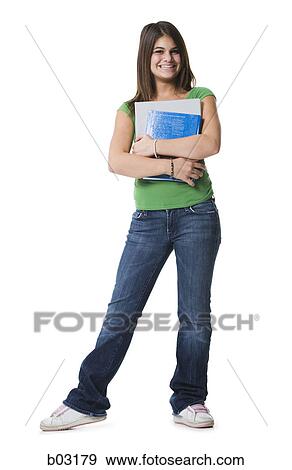 Stock Photo - Portrait of a teenage girl standing holding notebooks and smiling. Fotosearch
