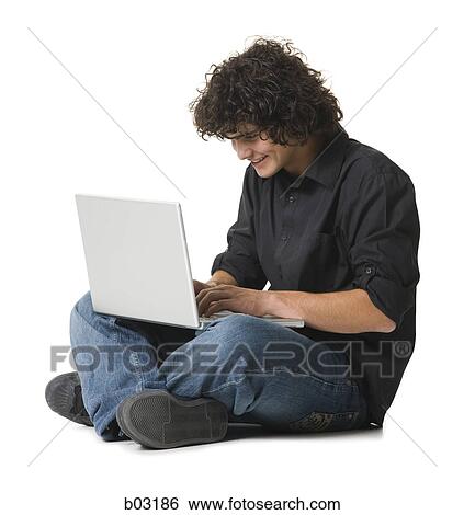 Teenage boy sitting and using a laptop View Large Photo Image Stock Photograph - Teenage boy sitting and using a laptop. Fotosearch