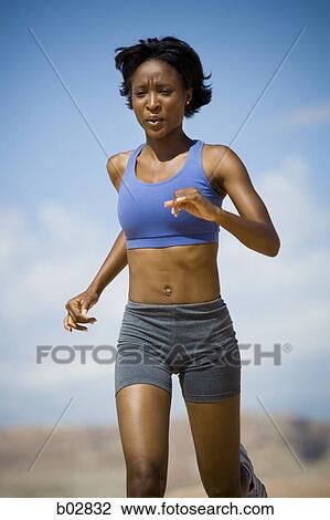 Low angle view of a young woman jogging View Large Photo Image Stock Image - Low angle view of a young woman jogging. Fotosearch