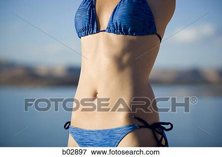Mid section view of a young woman in a bikini View Large Photo Image Stock Photo - Mid section view of a young woman in a bikini. Fotosearch