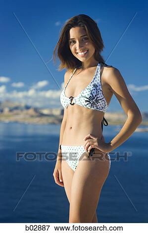 Stock Photo - Portrait of a young woman standing on the shore of a lake. Fotosearch