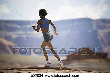 Picture - Rear view of a young woman jogging. Fotosearch