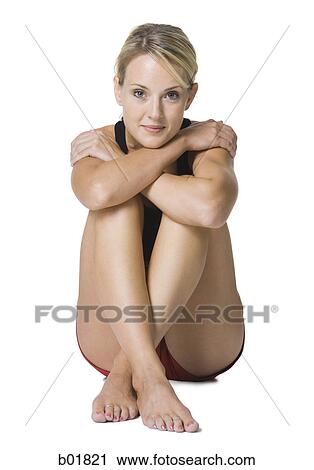 Stock Image - Portrait of a young woman sitting with her legs folded. Fotosearch