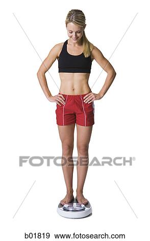 Young woman standing on a bathroom scale View Large Photo Image Stock Photo - Young woman standing on a bathroom scale. Fotosearch