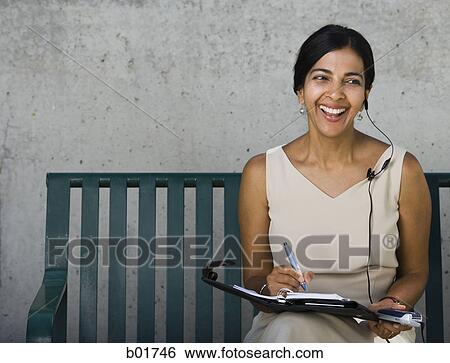 Businesswoman sitting on a bench and smiling View Large Photo Image Stock Photograph - Businesswoman sitting on a bench and smiling. Fotosearch