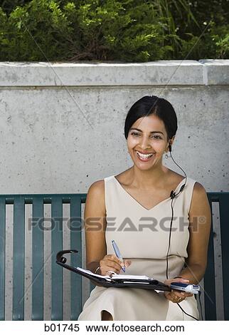 Businesswoman sitting on a bench and smiling View Large Photo Image Stock Photography - Businesswoman sitting on a bench and smiling. Fotosearch