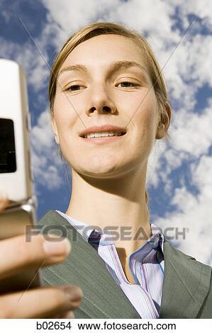 Close-up of a young woman holding a mobile phone View Large Photo Image Picture - Close-up of a young woman holding a mobile phone. Fotosearch