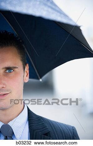 Stock Image - Portrait of a businessman under an umbrella. Fotosearch