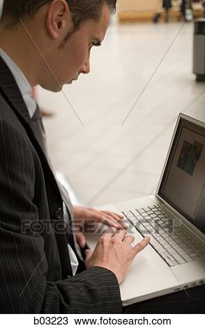 Stock Image - Profile of a businessman using a laptop. Fotosearch