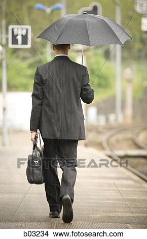 Rear view of a businessman walking on a railroad station platform View Large Photo Image Picture - Rear view of a businessman walking on a railroad station platform. Fotosearch