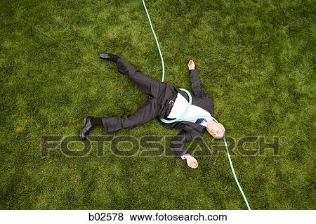 High angle view of a businessman with a hose lying down on a lawn View Large Photo Image Stock Photo - High angle view of a businessman with a hose lying down on a lawn. Fotosearch