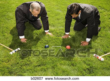 Stock Photo - High angle view of two businessmen playing croquet. Fotosearch