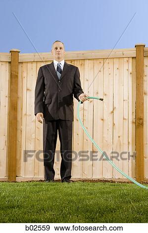 Low angle view of a businessman holding a hose standing in front of a wall View Large Photo Image Stock Photo - Low angle view of a businessman holding a hose standing in front of a wall. Fotosearch