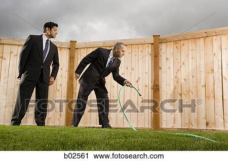 Low angle view of a businessman watering grass with another businessman looking at him View Large Photo Image Stock Image - Low angle view of a businessman watering grass with another businessman looking at him. Fotosearch
