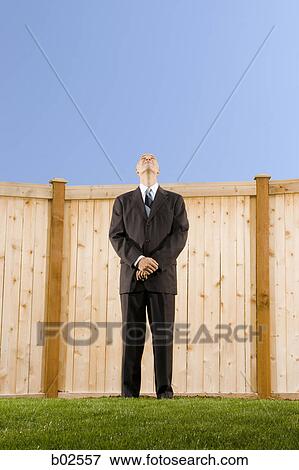 Low angle view of a businessman standing in front of a wall looking up View Large Photo Image Stock Photo - Low angle view of a businessman standing in front of a wall looking up. Fotosearch