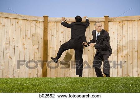 Stock Image - Low angle view of two businessmen playing on a lawn. Fotosearch