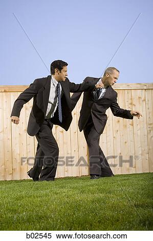 Stock Photography - Low angle view of two businessmen playing and rough housing. Fotosearch