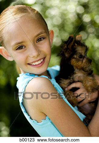 Portrait of a girl carrying a puppy View Large Photo Image Stock Image - Portrait of a girl carrying a puppy. Fotosearch