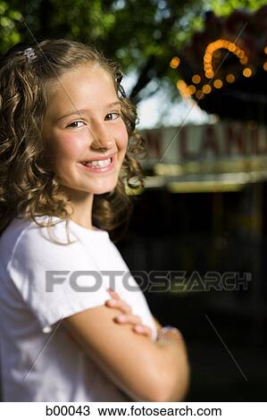 Stock Image - Side profile of a girl standing with her arms crossed. Fotosearch