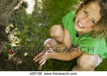 Stock Photo - Portrait of a girl playing with mud. Fotosearch
