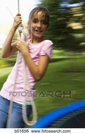 Portrait of a girl swinging from a rope View Large Photo Image Stock Photograph - Portrait of a girl swinging from a rope. Fotosearch