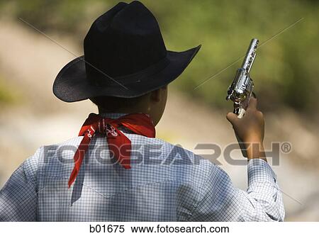 Stock Photography - Rear view of a boy in a cowboy costume holding a toy gun. Fotosearch
