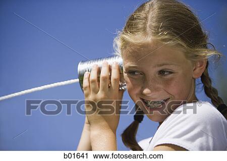 Low angle view of a girl listening into a tin can phone View Large Photo Image Stock Image - Low angle view of a girl listening into a tin can phone. Fotosearch