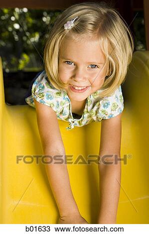 Stock Image - Portrait of a girl lying on a slide. Fotosearch