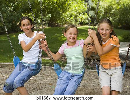 Portrait of three girls sitting on swings View Large Photo Image Stock Photo - Portrait of three girls sitting on swings. Fotosearch