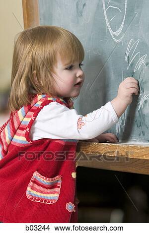 Profile of a baby girl writing on a blackboard View Large Photo Image Picture - Profile of a baby girl writing on a blackboard. Fotosearch