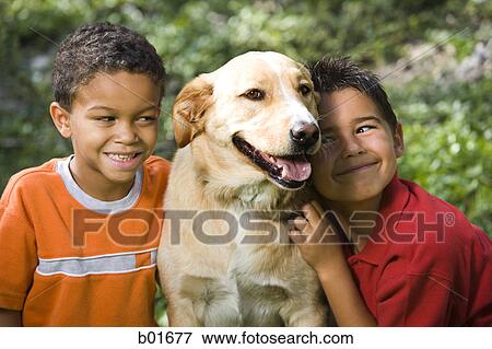Two boys sitting with a dog View Large Photo Image Stock Photo - Two boys sitting with a dog. Fotosearch