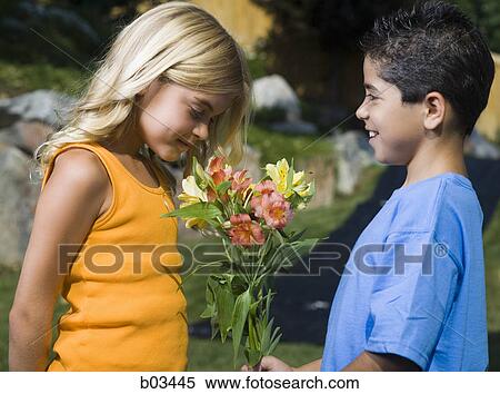 Stock Photography - Young man drinking water from a water bottle held by a young woman. Fotosearch