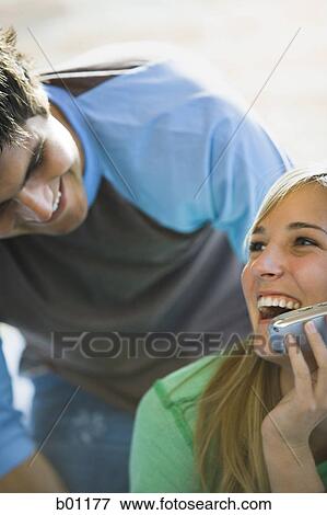 Close-up of a young man bending over a young woman talking on a mobile phone View Large Photo Image Stock Photo - Close-up of a young man bending over a young woman talking on a mobile phone. Fotosearch
