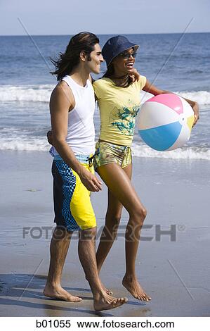 Profile of a young couple walking on the beach View Large Photo Image Stock Photography - Profile of a young couple walking on the beach. Fotosearch