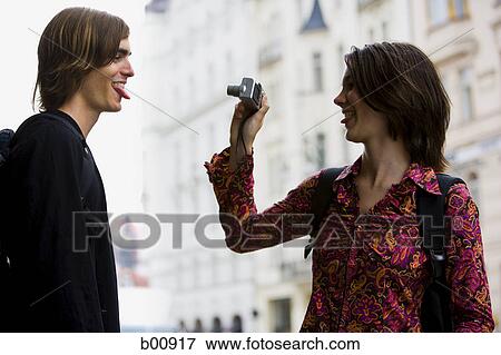 Profile of a young woman taking a young man's photograph View Large Photo Image Stock Photo - Profile of a young woman taking a young man's photograph. Fotosearch