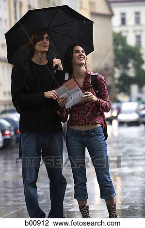 Young man and a young woman standing on a street with a map View Large Photo Image Stock Image - Young man and a young woman standing on a street with a map. Fotosearch